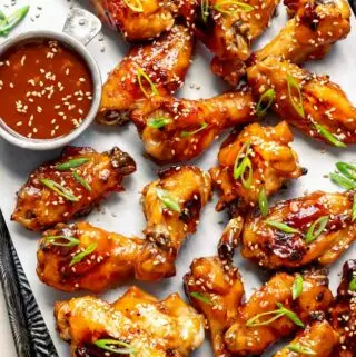 Thai Chicken Wings on a baking sheet with green onions and extra sauce