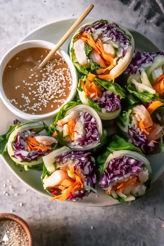 keto spring rolls, made of collard greens instead of rice paper wraps. Shown with peanut sauce to dip.