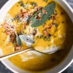 recipes for butternut squash soup in a bowl with a spoon and sage on top