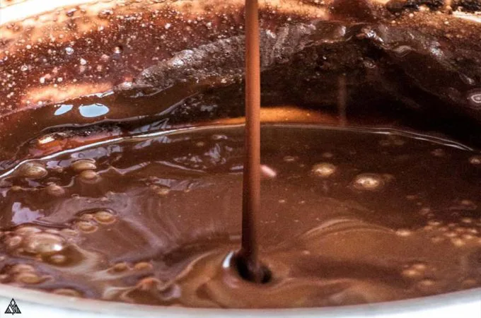 pouring low carb chocolate syrup into a bowl
