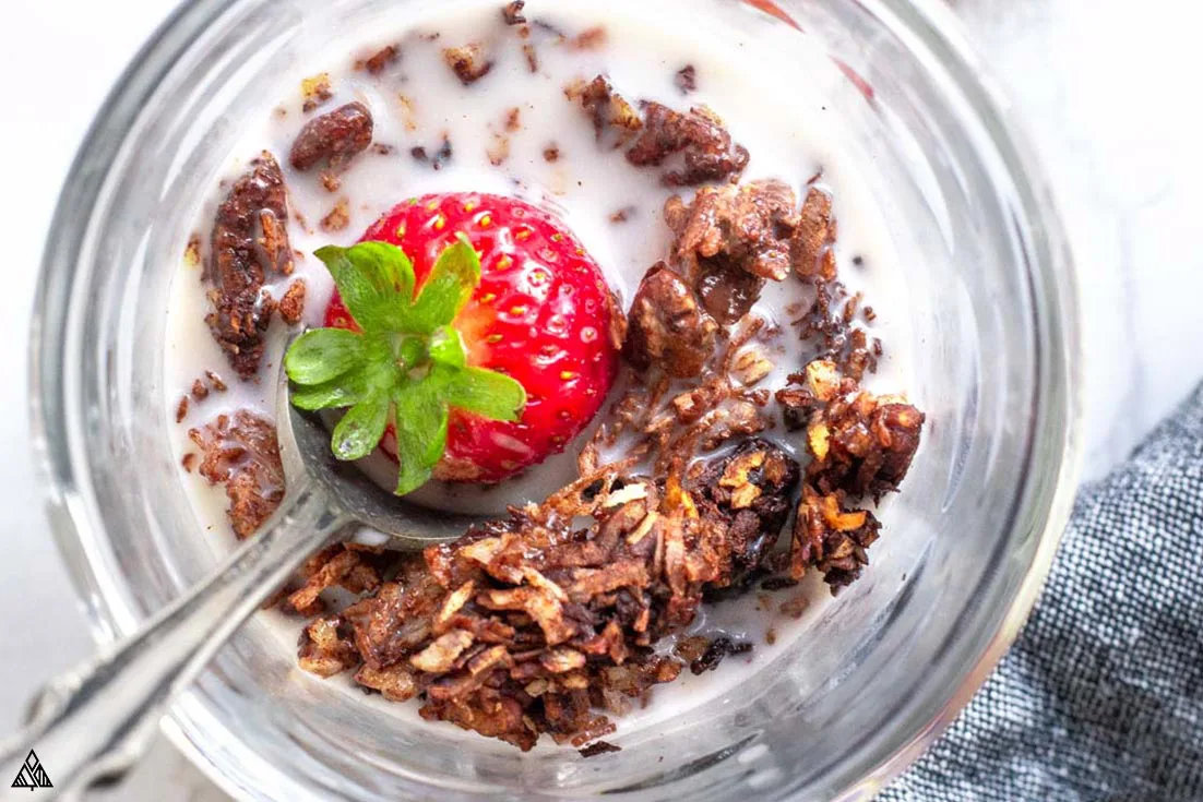 Top view of low carb chocolate granola in a glass topped with strawberry