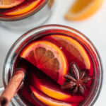 Top view of a glass of mulled wine topped with slices of lemons