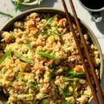 fried cauliflower rice in a bowl with chop sticks and green onions