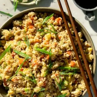 fried cauliflower rice in a bowl with chop sticks and green onions