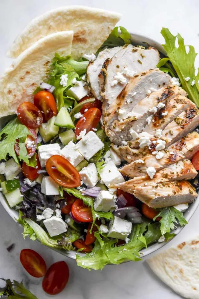 Closer look of greek chicken salad in a bowl with pita in the corner. A healthy and fresh keto chicken recipes