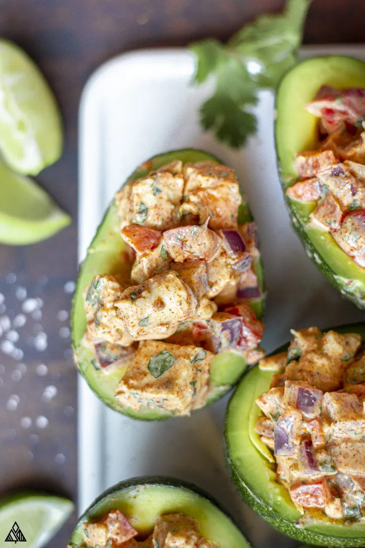 Halved avocado topped with mexican keto chicken salad recipe
