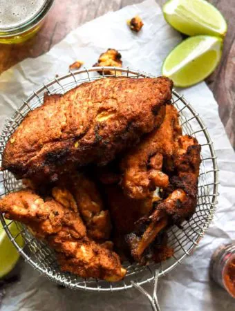 basket full of low carb fried chicken with limes and hot sauce