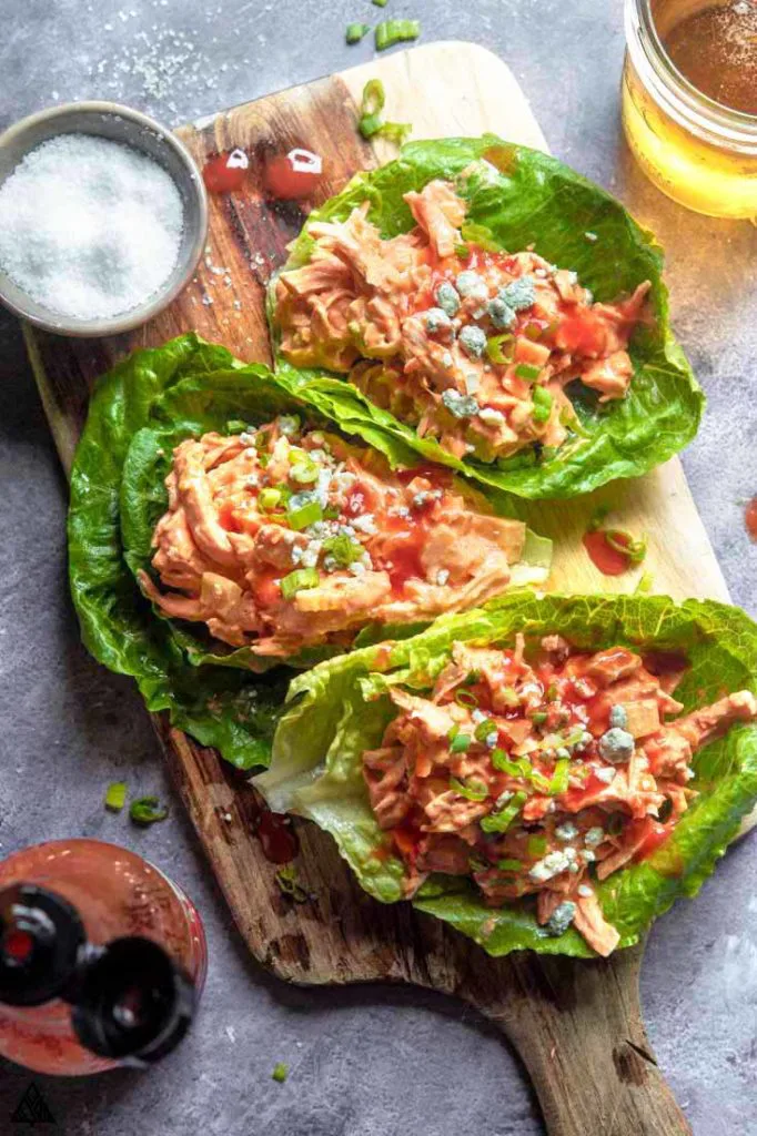 buffalo chicken salad wrapped in lettuce, on a cutting board with a beer in the corner. On a list of keto chicken recipes