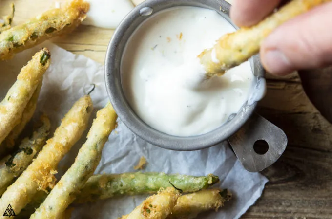 Low carb fried green bean dipped into a small bowl of mayo