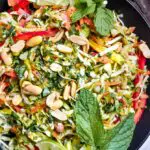 Thai chicken salad in a bowl with herbs and limes