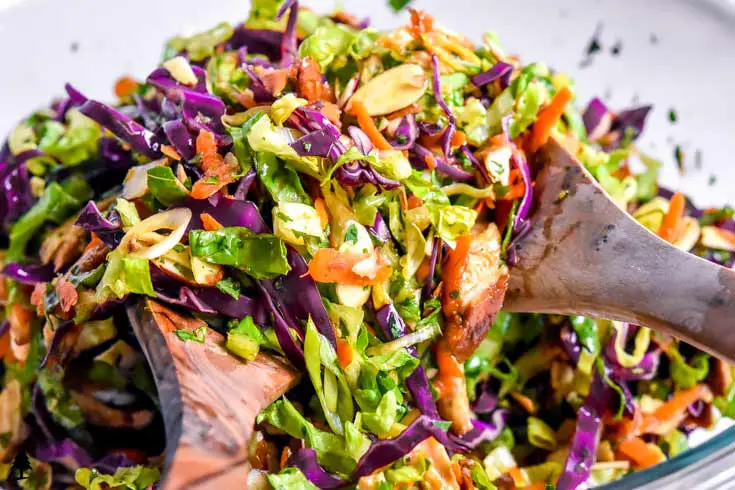 Chinese chicken salad being tossed with Asian dressing