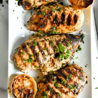 mediterranean chicken marinade on a plate with lemon slices and parsley