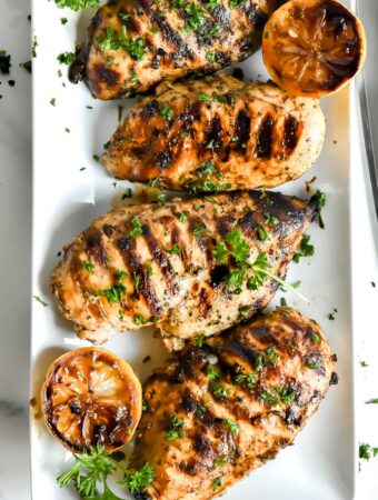 mediterranean chicken marinade on a plate with lemon slices and parsley