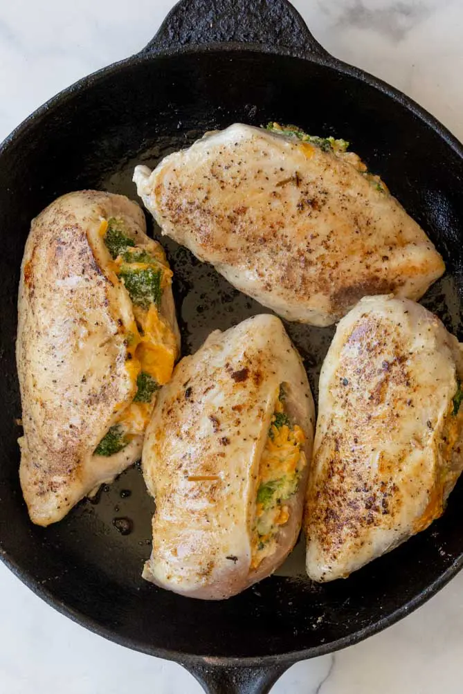 broccoli and cheese stuffed chicken in a cast iron pan