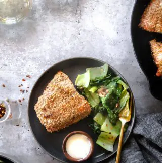 Top view of breaded salmon on a plate with vegetable sided and a fork