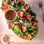 spinach strawberry salad on a platter with balsamic dressing and feta