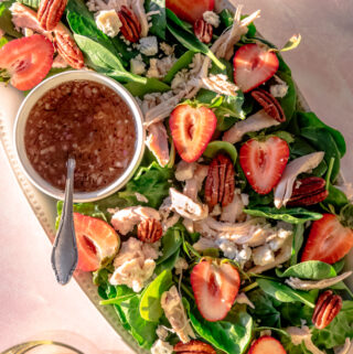 close up of strawberry salad with dressing and spinach