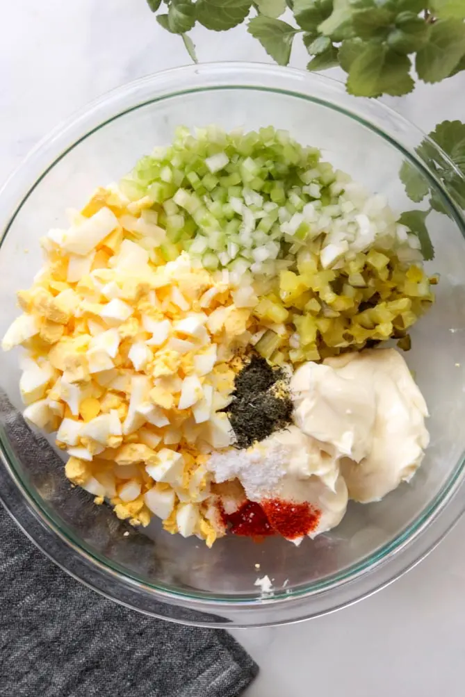 easy egg salad ingredients in a bowl before they have been mixed together.
