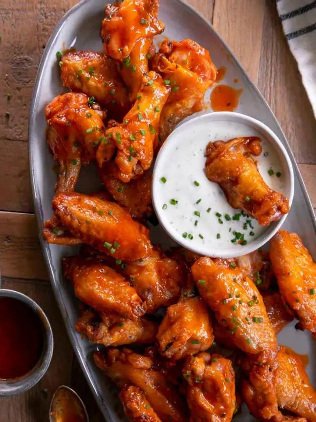 buffalo baked chicken wings, shown with ranch to dip and fresh chives.