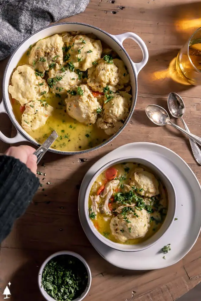 keto chicken and dumplings in a pot, and someone is ladling it into a bowl of soup