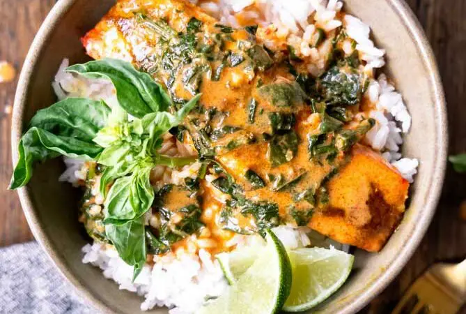 bowl of curry salmon over rice with limes