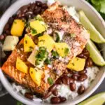 bowl of jerk salmon over beans and rice with limes