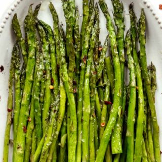 oven roasted asparagus on a tray with red pepper flakes