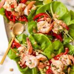 shrimp lettuce wraps recipe on a platter with peanut sauce and peants on top
