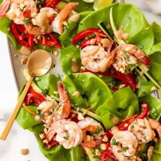 shrimp lettuce wraps recipe on a platter with peanut sauce and peants on top
