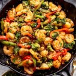shrimp stir fry in a cast iron skillet with cilantro and rice