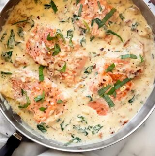 tuscan salmon recipe in a large pan with basil on top and red pepper flakes