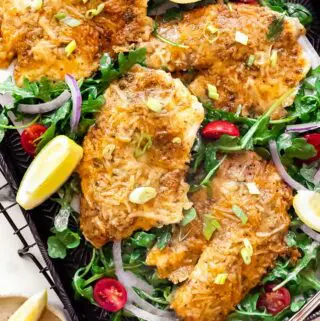 parmesan crusted tilapia on a baking sheet with lettuce