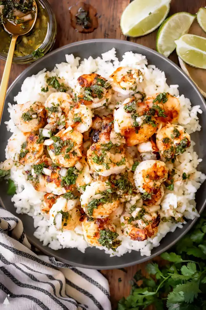 shrimp chimichurri on a plate with rice and limes