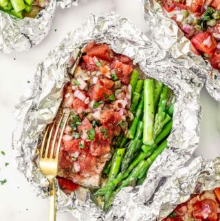 oven baked salmon in foil covered in tomatoes and capers