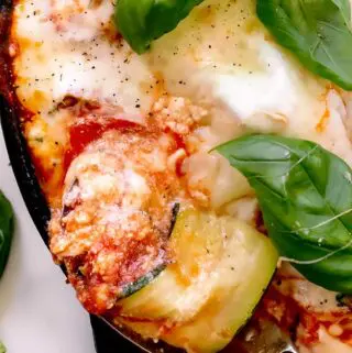 zucchini lasagna roll ups in a baking dish being removed by a spoon