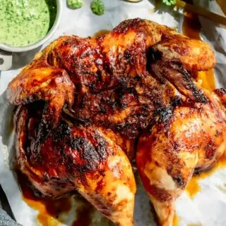 peru roasted chicken on a baking sheet with green sauce on the side