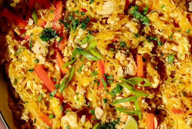 spaghetti squash pad thai in a pan with lime and cilantro on top