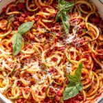 zucchini spaghetti in a pot with fresh basil on top