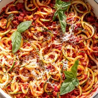 zucchini spaghetti in a pot with fresh basil on top