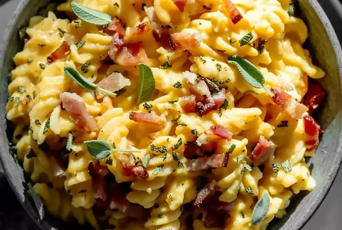 butternut squash pasta sauce with bacon and sage on top in a black bowl