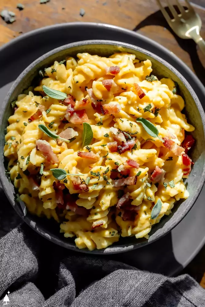 butternut squash sauce with bacon and sage on top in a black bowl