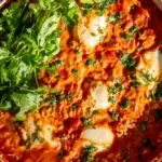 shakshuka recipe in a large pan with cilantro on top and a fresh baguette