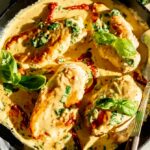 creamy tuscan chicken in a skillet with basil on top