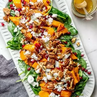 butternut squash salad on a platter with dressing on the side