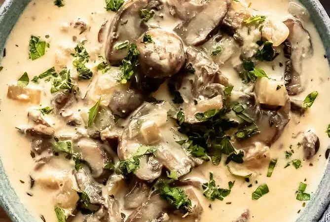 mushroom soup recipe in a bowl with parsley and mushrooms on top