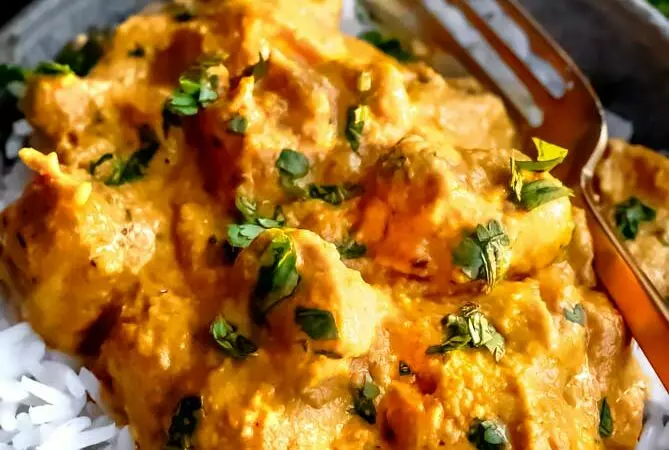 easy chicken korma recipe in a bowl with cilantro on top and over rice