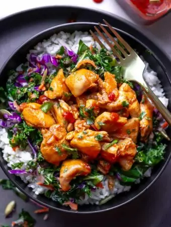 harissa honey chicken in a bowl over. rice and salad