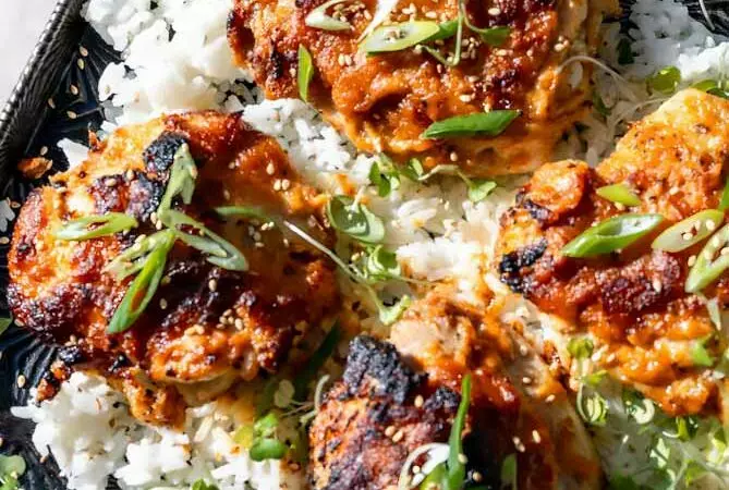miso chicken thighs on a baking sheet with rice and green onions