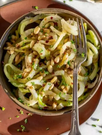 simple kohlrabi recipe for kohlrabi noodles in a bowl with pine nuts on top