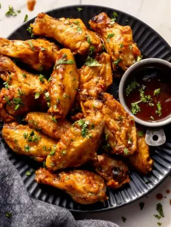 tequila lime wings recipe on a plate with extra sauce and cilantro